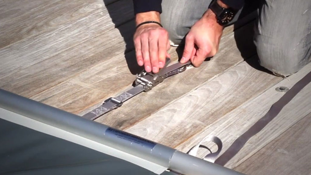 Détail d'une barre aluminium de bâche piscine fixée sur dalle béton